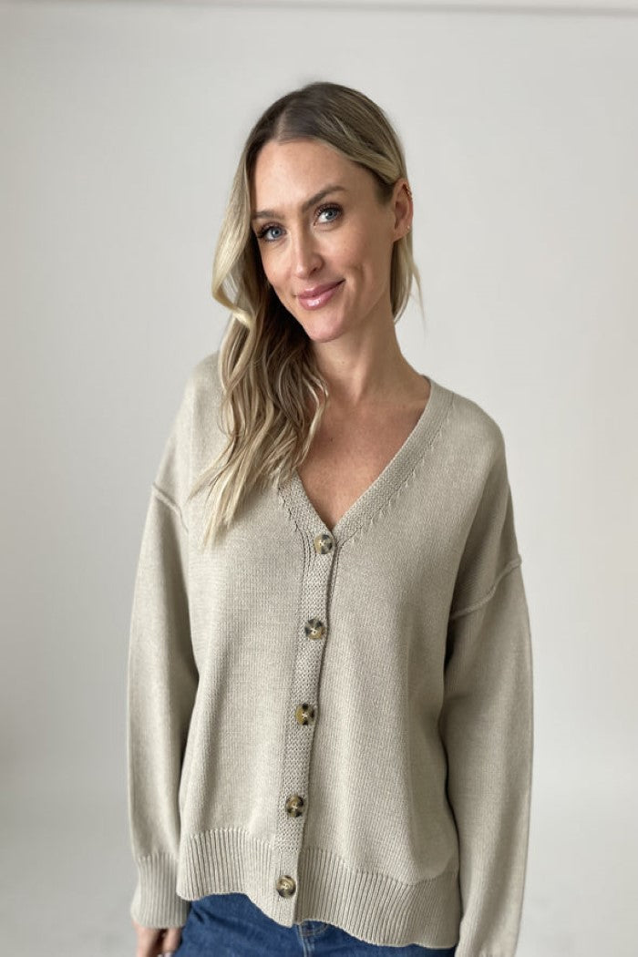 Woman wearing a beige cardigan against a plain background