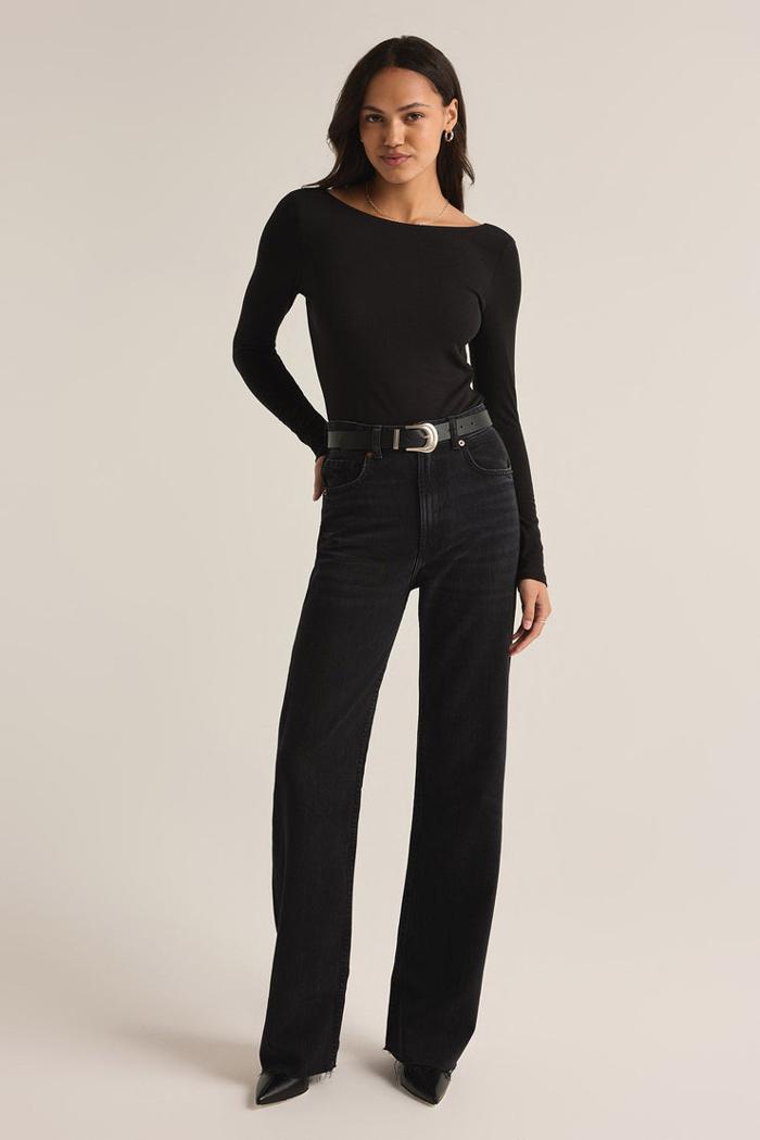 A model wearing a long-sleeved, fitted black bodysuit with a classic crew neck and mid-calf black pants.