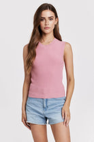 Woman wearing a pink sleeveless top and denim shorts on a white background