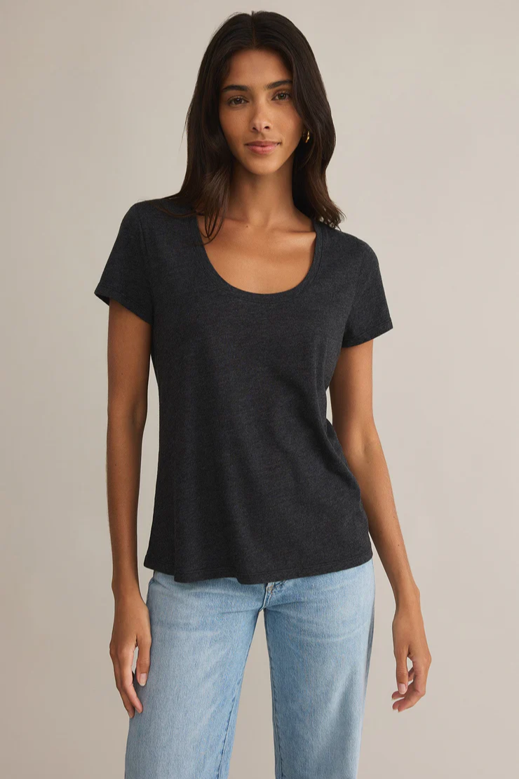 A woman wearing a black scoop neck tee and blue jeans.