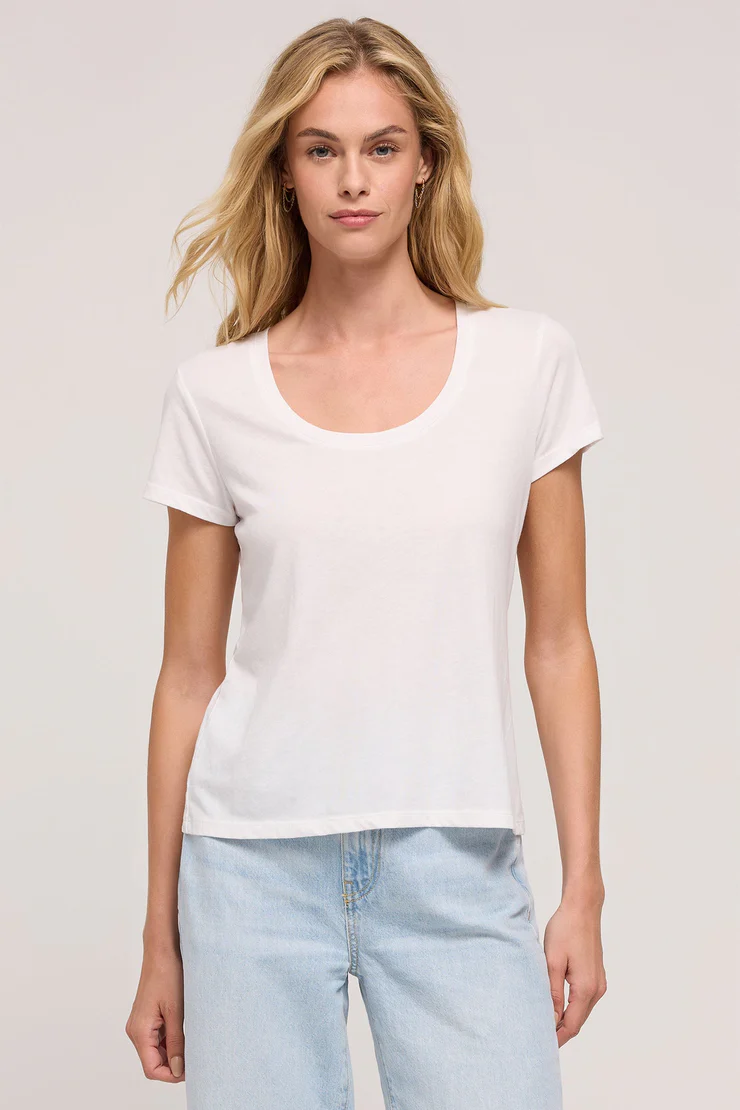 A woman wearing a black scoop neck tee and blue jeans.