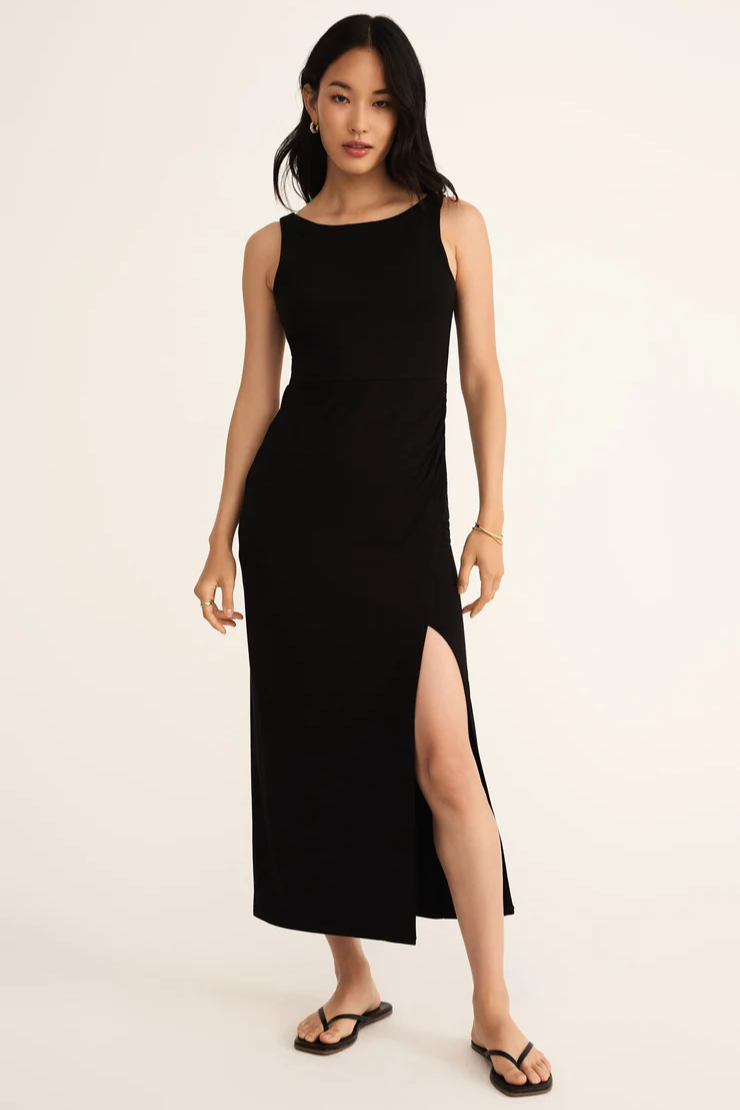 Woman wearing a black sleeveless dress with a slit on a beige background