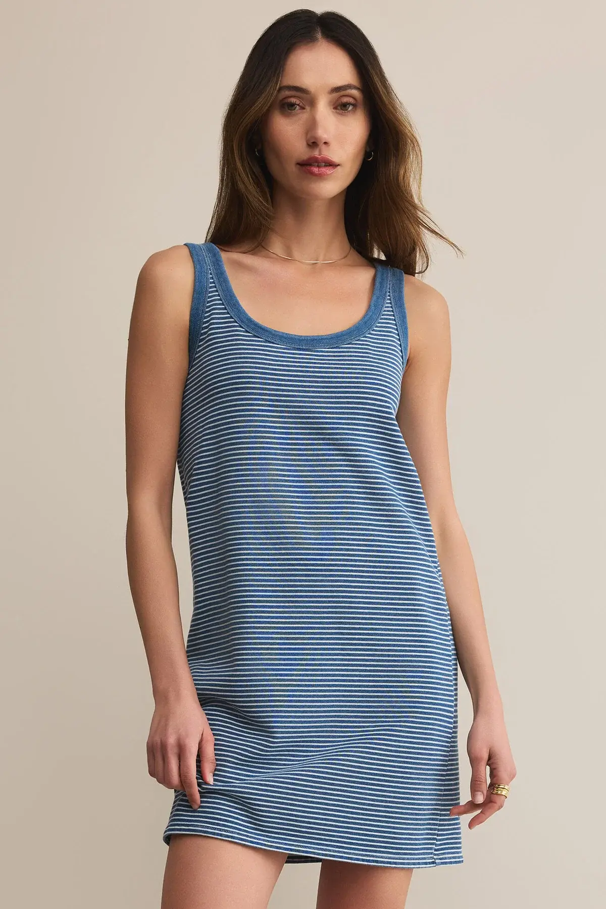 Woman wearing a blue striped dress against a beige background