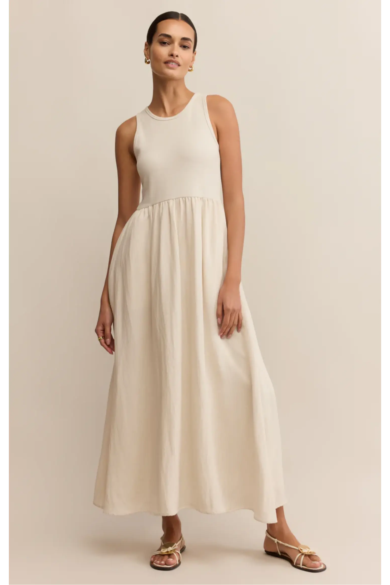 Woman wearing a white sleeveless dress against a beige background