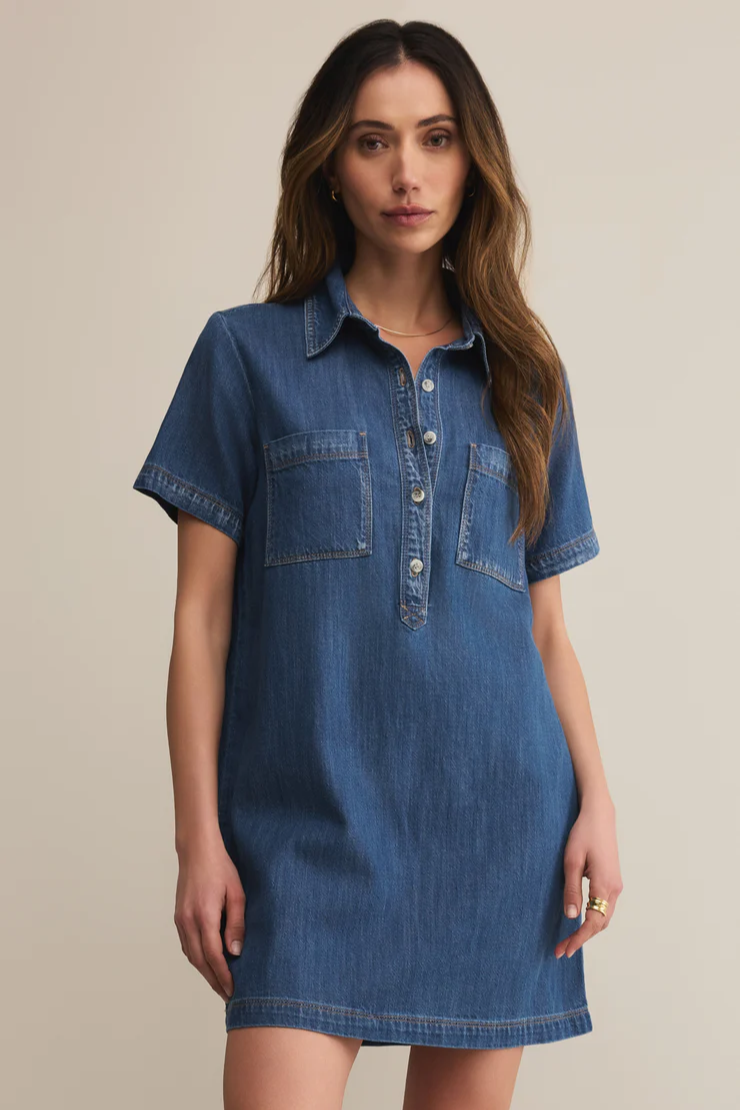 Woman wearing a blue denim dress against a beige background