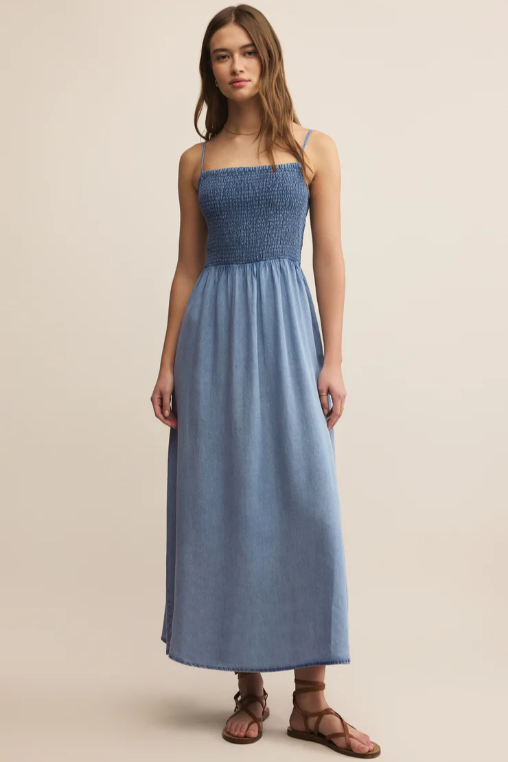 Woman wearing a blue strapless dress against a beige background