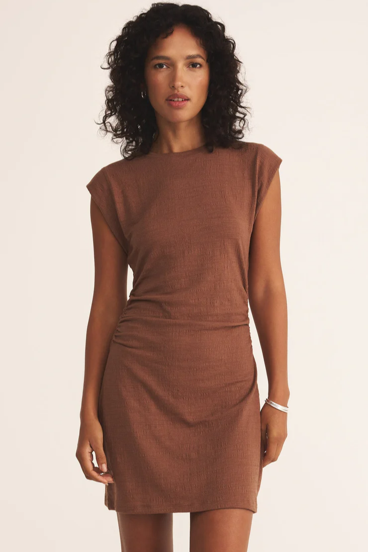 Woman wearing a brown dress against a plain background