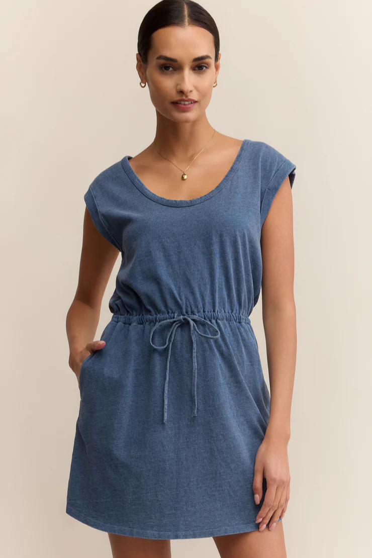 Woman wearing a blue dress against a beige background