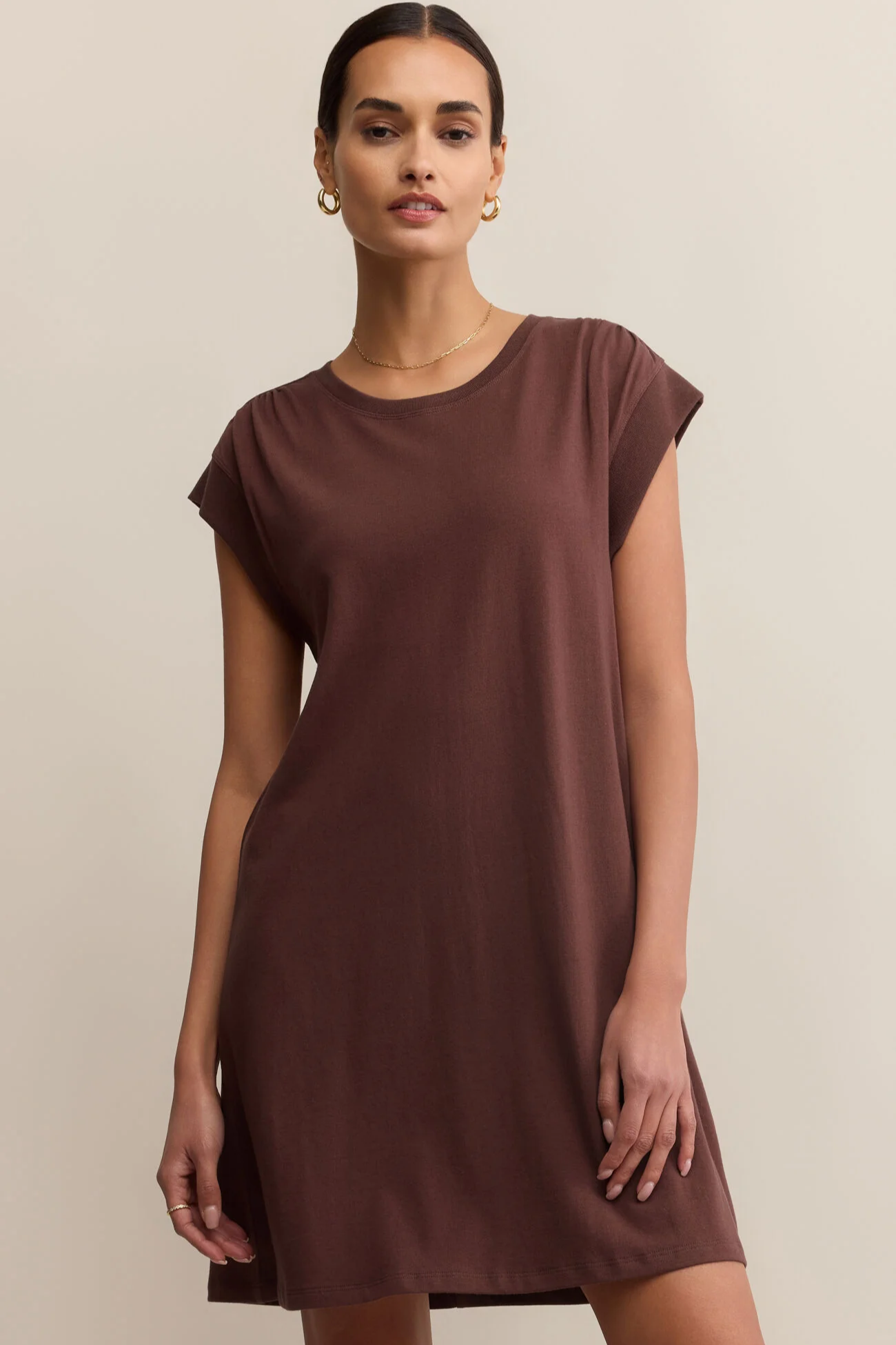 Woman wearing a brown dress against a beige background