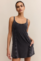 Woman wearing a black slip dress against a beige background