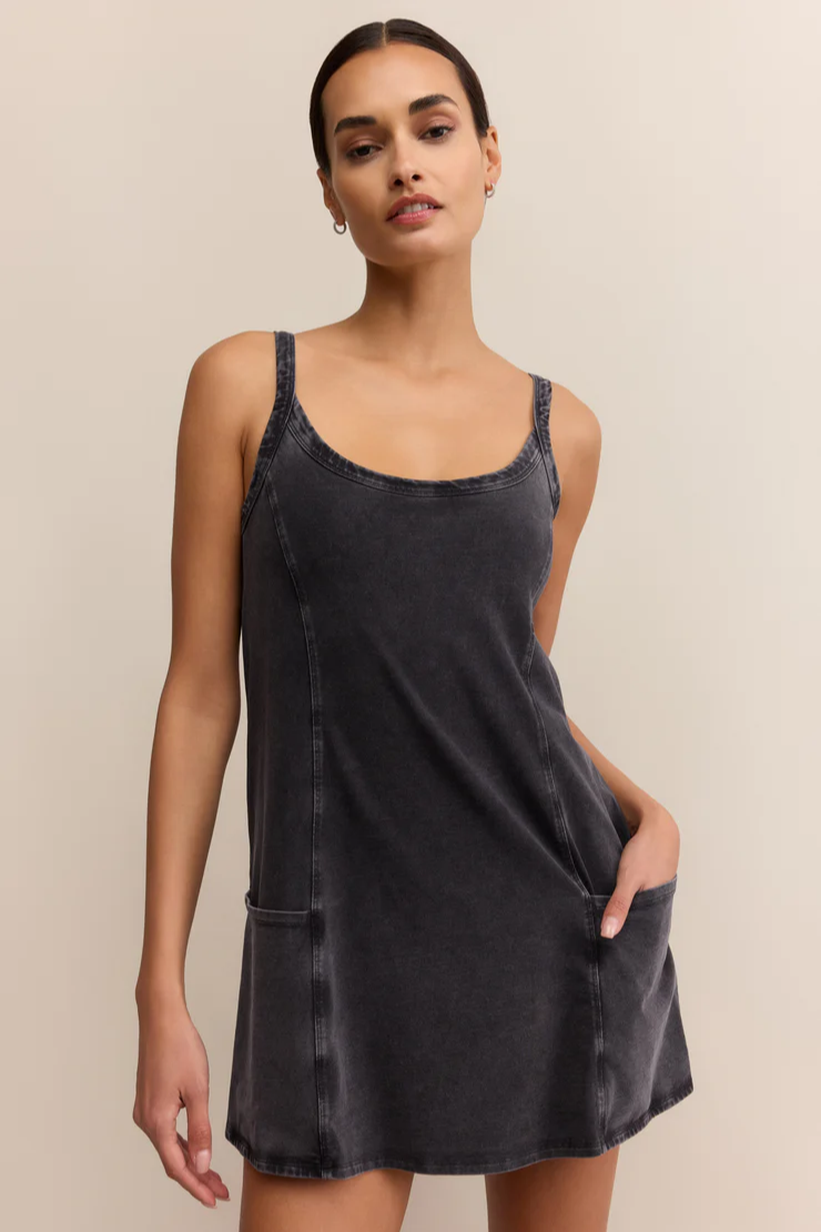 Woman wearing a black slip dress against a beige background