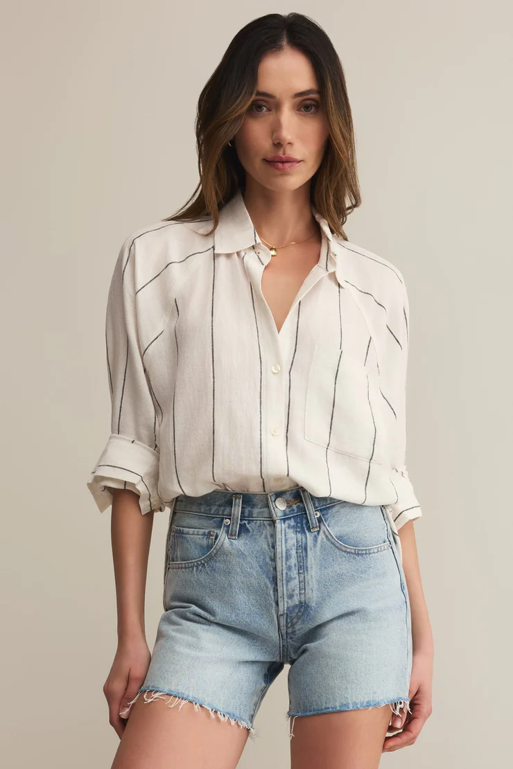 Woman wearing a white blouse and denim shorts against a plain background