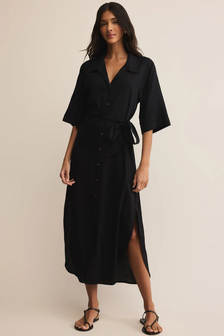 Woman wearing a black dress with a belt on a beige background