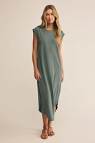 Woman wearing a long green dress on a beige background