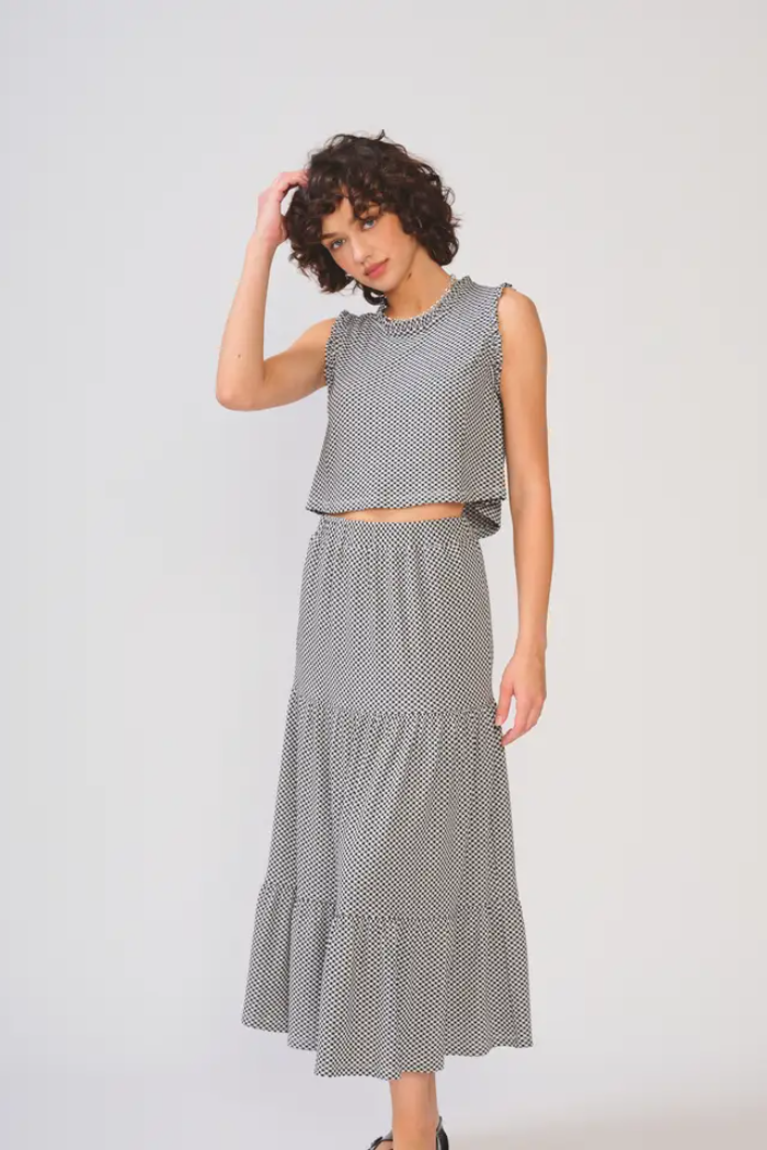 Woman wearing a gray polka dot top and skirt on a white background