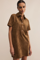 Woman wearing a brown suede dress against a beige background