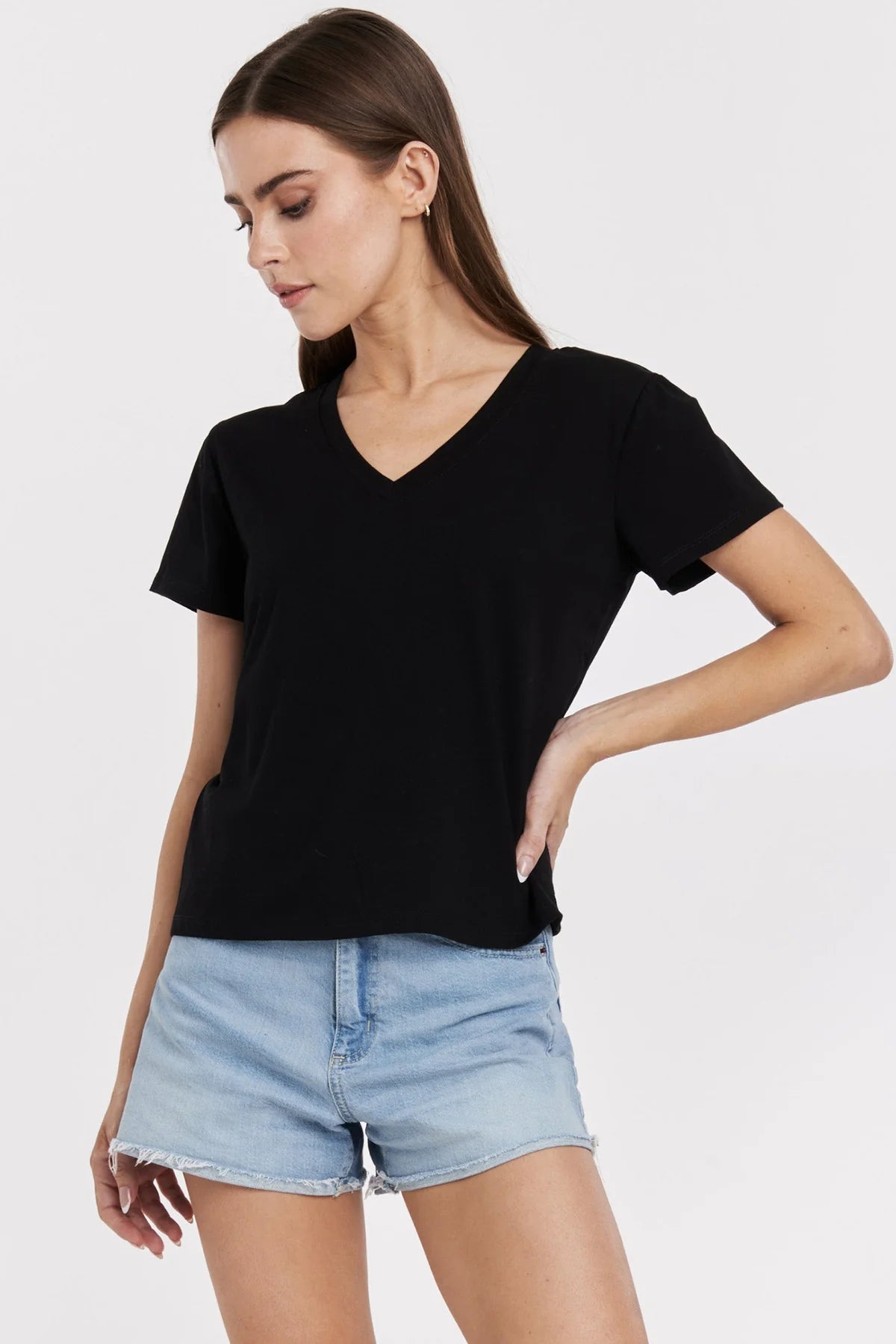 Woman wearing a black t-shirt and light blue denim shorts on a white background