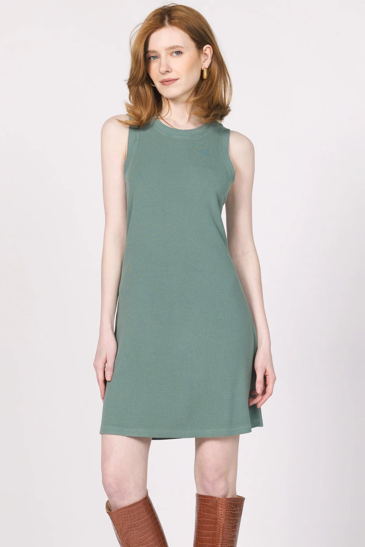 Woman wearing a green dress with brown boots on a white background