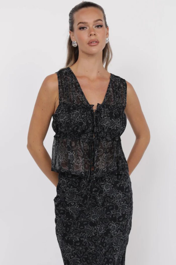 Woman wearing a black floral dress against a white background
