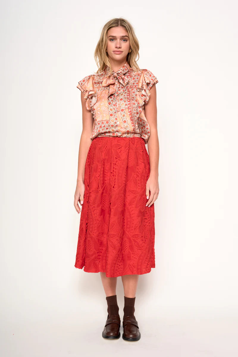 Woman wearing a floral blouse and red skirt on a white background