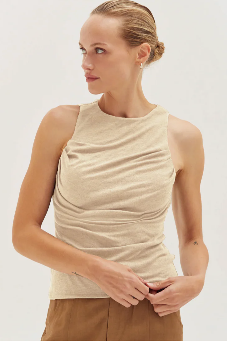 Woman wearing a beige sleeveless top against a white background