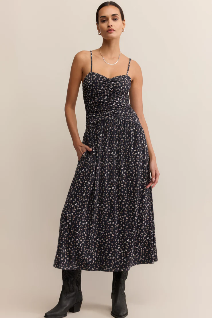 Woman wearing a black floral dress against a beige background