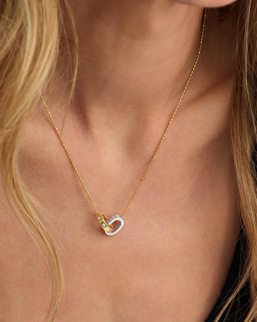 Blonde model wearing Ashley Duo Necklace gold and silver interlocked rings at neckline