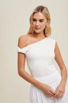 Woman wearing a white one-shoulder dress against a plain background