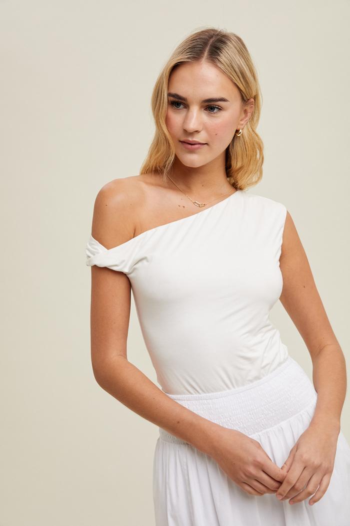 Woman wearing a white one-shoulder dress against a plain background