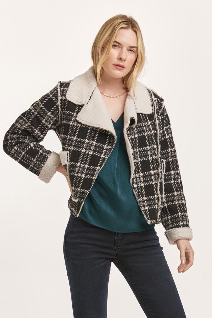 Woman wearing a plaid jacket with white fur lining on a white background