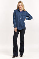 Woman wearing a blue denim shirt and black jeans on a white background