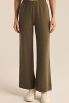 Person wearing olive green wide-leg pants on a beige background