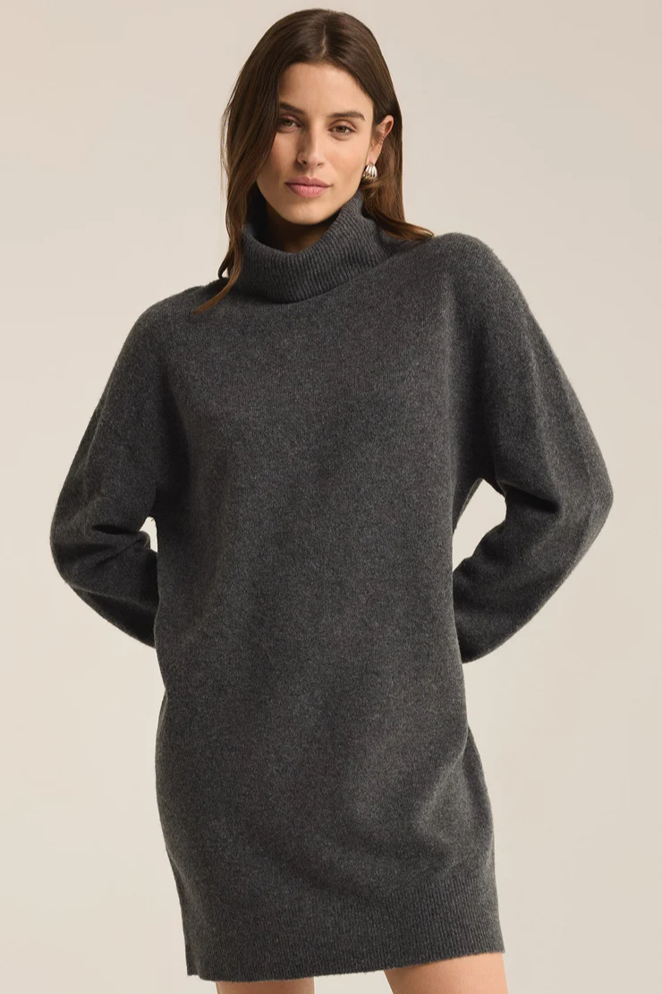 Woman wearing a dark gray turtleneck dress against a plain background