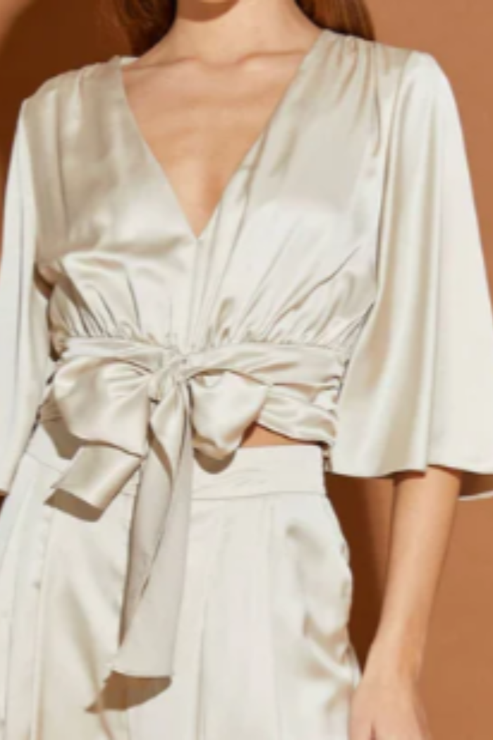 Beige satin dress with a tie waist on a brown background