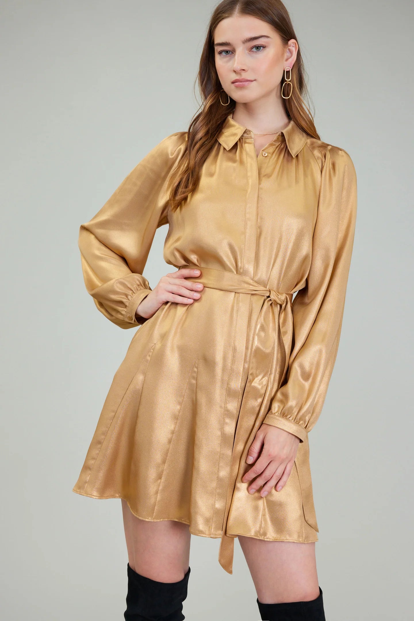 Woman wearing a gold satin dress against a plain background