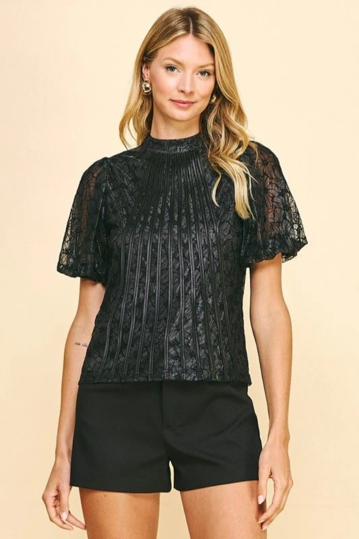 Woman wearing a black lace top and shorts on a beige background