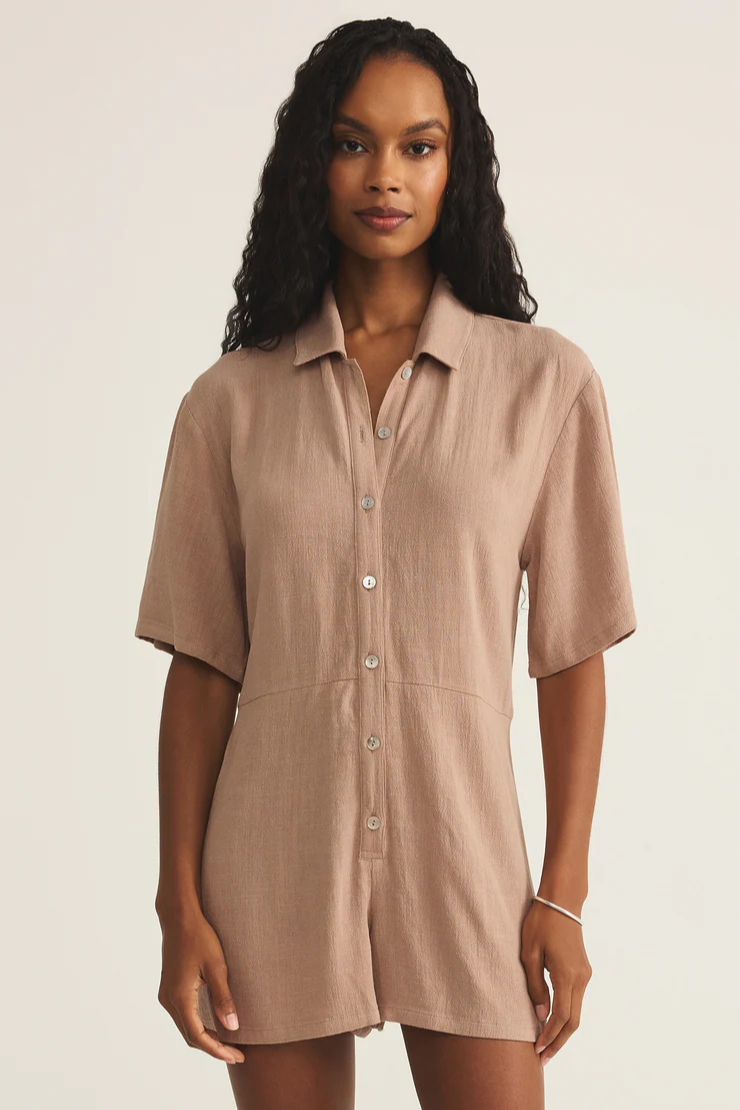 Woman wearing a beige button-up dress against a plain background
