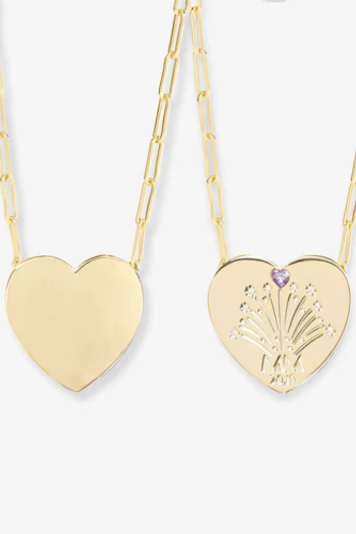 Gold heart-shaped necklaces with one featuring a purple gemstone on a white background