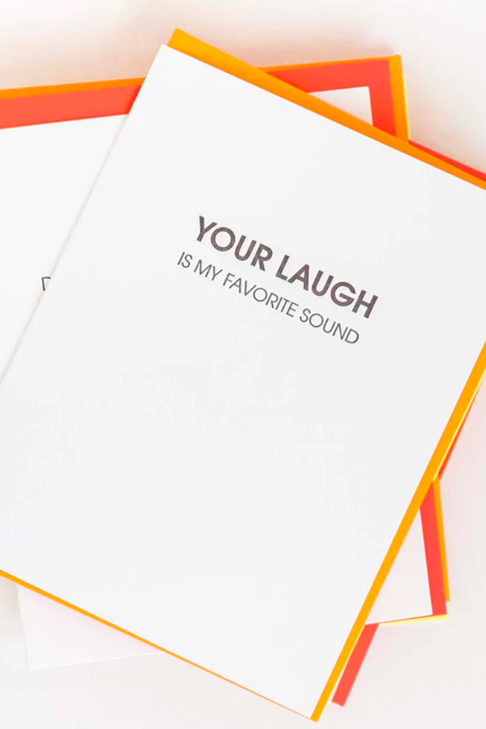 Notebook with 'Your laugh is my favorite sound' text on a light background