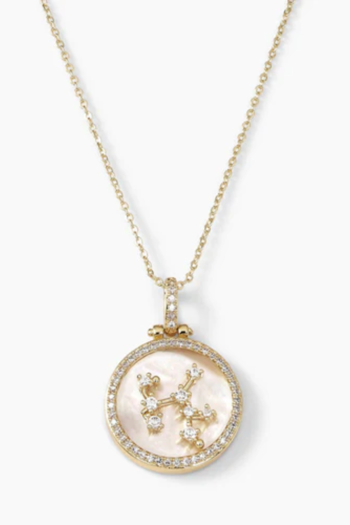 Gold necklace with a pendant featuring a zodiac symbol on a white background