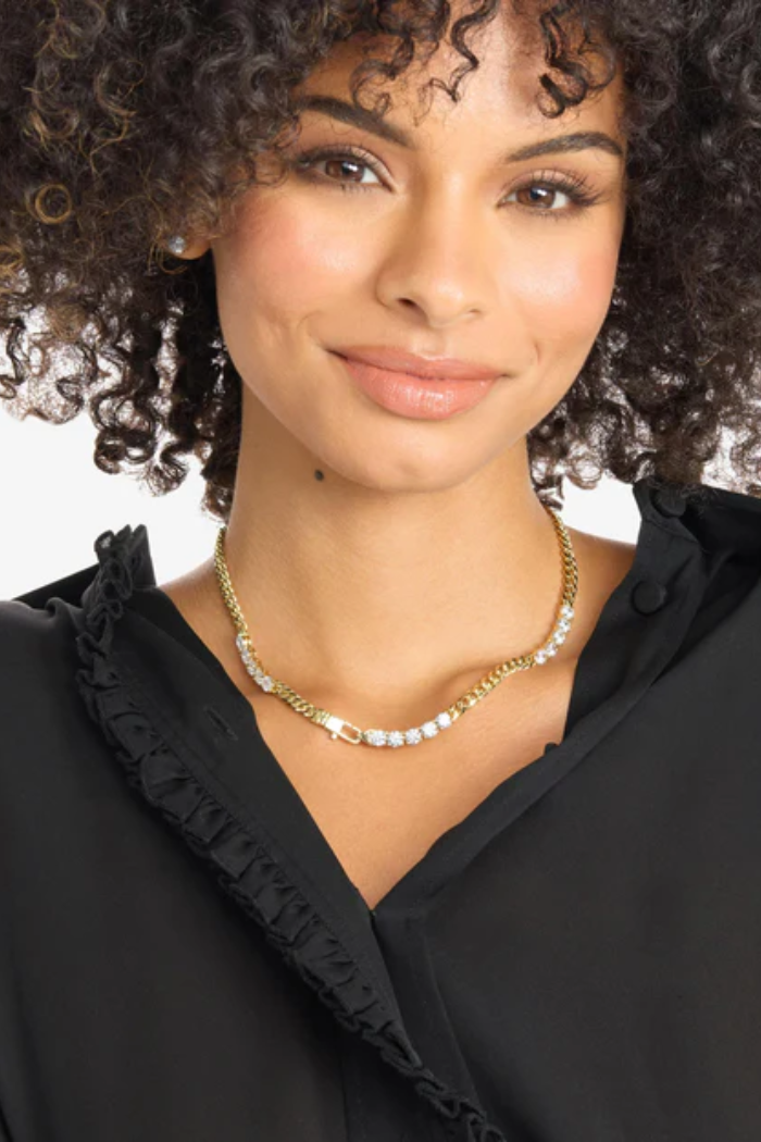 Woman wearing a black top and gold necklace with a white background
