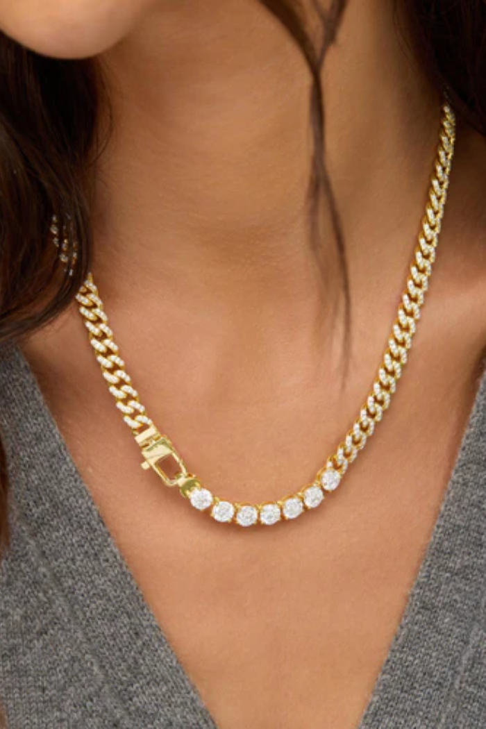 Gold chain necklace with a clasp worn by a person