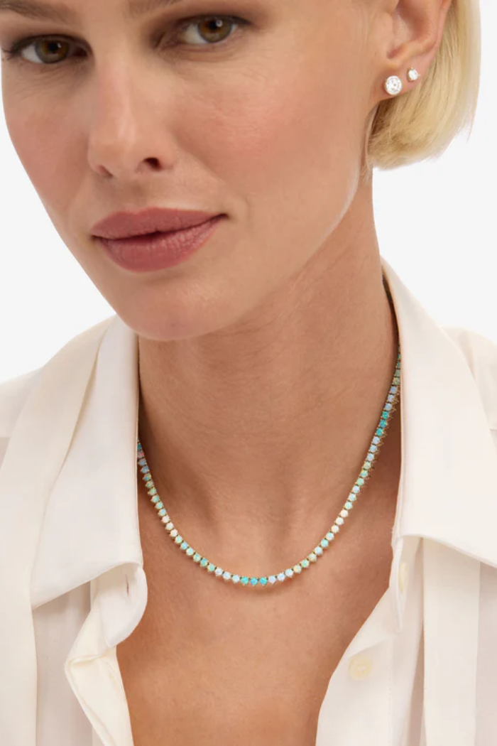 Close-up of a woman wearing a turquoise beaded necklace with a white shirt.