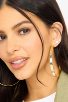Close-up of a woman wearing gold hoop earrings with a blurred background