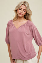 Woman wearing a pink blouse against a beige background