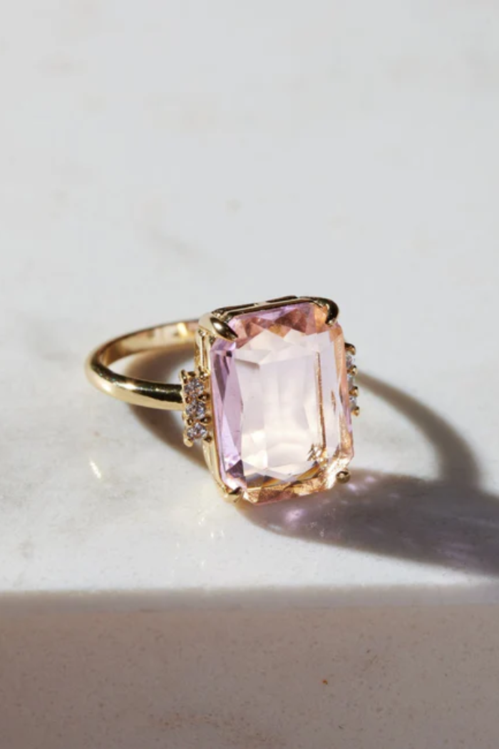 Gold ring with a pink gemstone on a light background