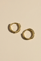 Gold hoop earrings on a beige background