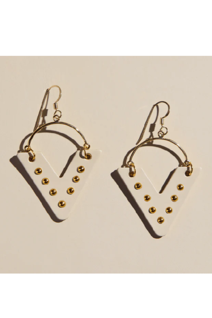 Pair of earrings with gold accents on a beige background