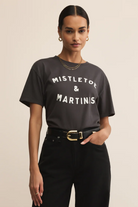 Woman wearing a black t-shirt with 'MISTLETOE & MARTINIS' text on a beige background