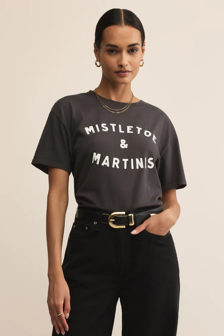 Woman wearing a black t-shirt with 'MISTLETOE & MARTINIS' text on a beige background